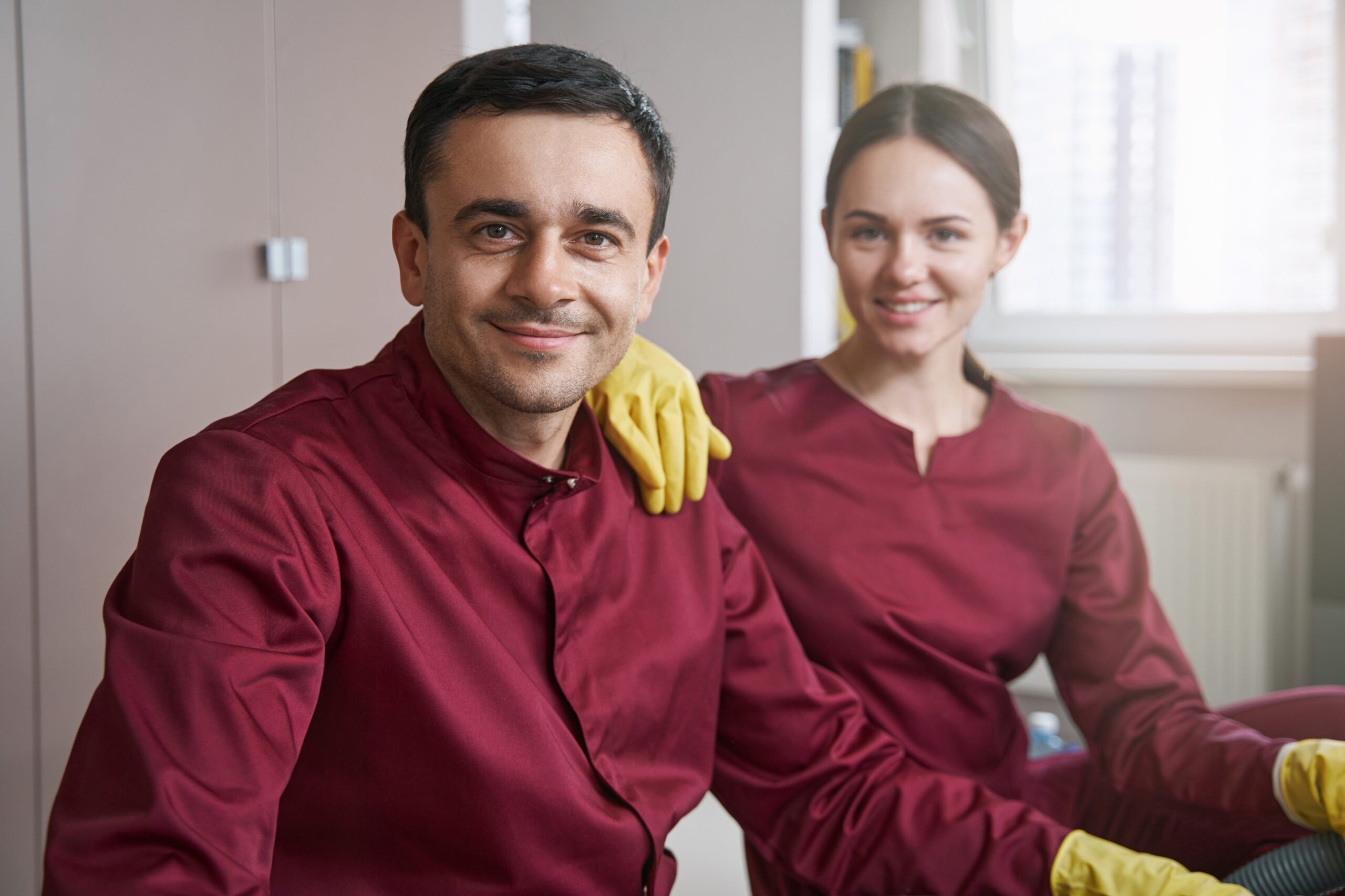 Smiling janitorial personnel in uniforms posing for camera in workplace