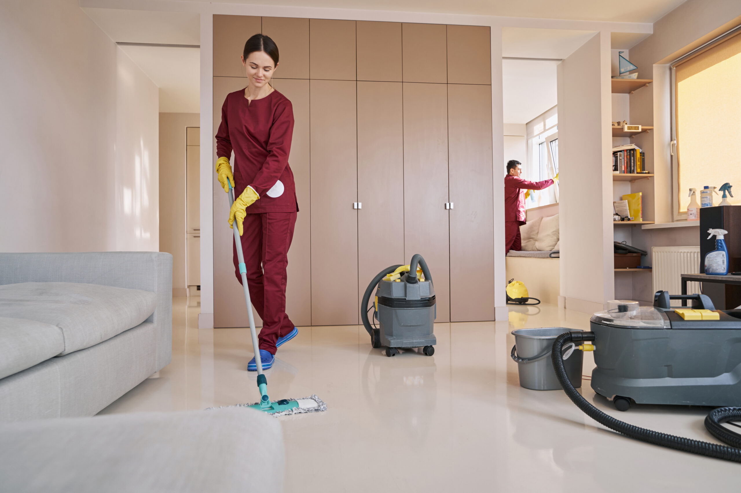 Two uniformed Caucasian cleaners doing professional housecleaning